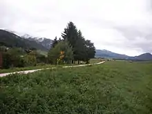 Paysage d'une vallée avec au premier plan un chemin et au fond des montagnes.