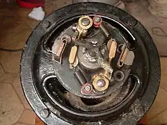 Vue de l'intérieur du coupleur centrifuge. À remarquer les deux masselottes en bronze maintenues chacune par un ressort de force différente afin que les contacts se fassent en deux temps lors de l’accélération du moteur