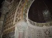 Vue partielle de la partie supérieure du mihrab, montrant la demi-coupole peinte, réalisée en bois cintré, de la niche, ainsi que les carreaux lustrés ornant l'intérieur et l'encadrement de celle-ci.