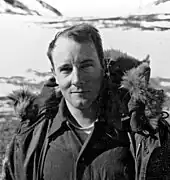 Photo en noir et blanc d'un homme d'une trentaine d'années avec une veste en fourrure.