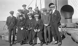 Photographie montrant les joueurs canadiens en compagnie d'un officier et d'une femme (non identifiée) sur le pont du bateau.