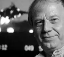 Photographie en noir et blanc de Wolfgang Petersen, dont on ne voit que la tête. Il sourit légèrement