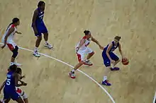 Meneuse française dribblant dos au panier avec une adversaire dans son dos. D'autres joueuses luttent pour la position.