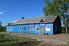 Photographie d'un bâtiment en bois bleu ne possédant pas d'étage, avec un toit en pente.